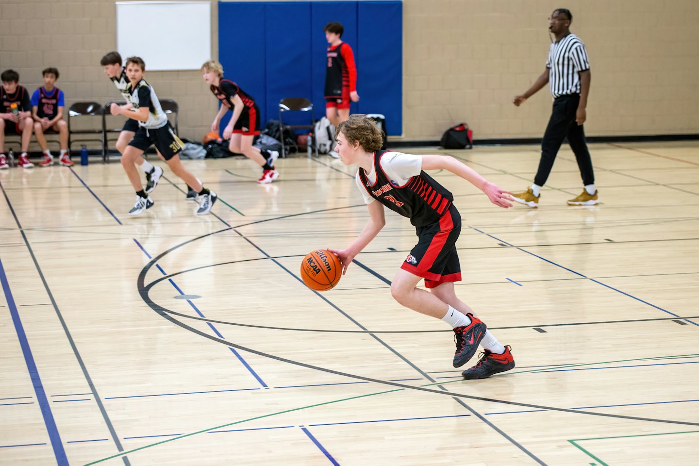 Young basketball player dribbles down the court during a game.