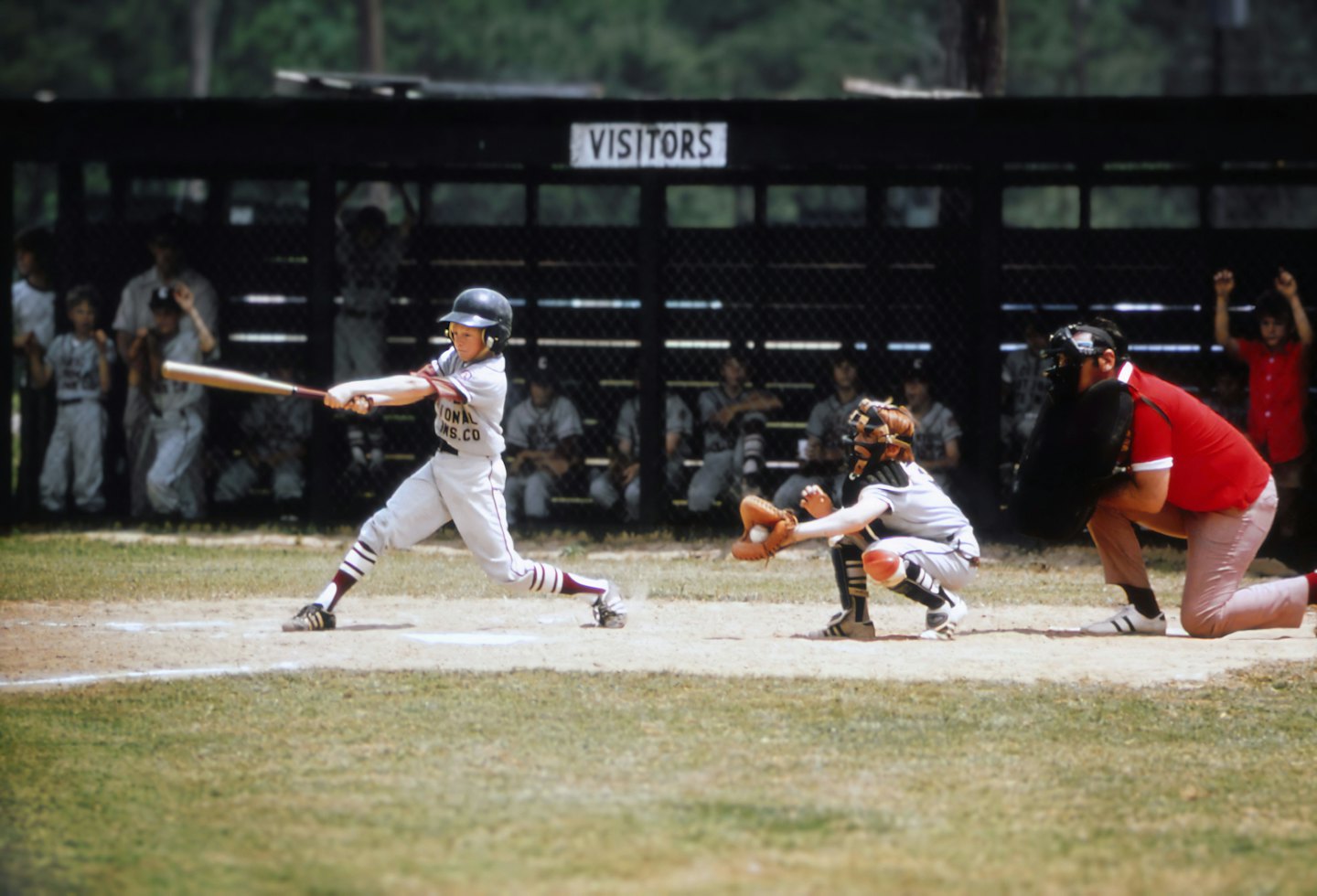 Young boy swings a baseball bat at home plate during a game.